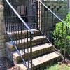 Handrails down the back patio steps with a patio gate at the top of the steps between the columns